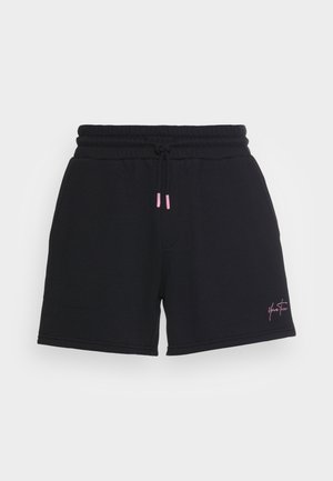 Schwarze Freizeithose mit elastischem Bund, pinkfarbenen Kordelenden und kleinem pinkfarbenem Schriftzug auf dem linken Bein.