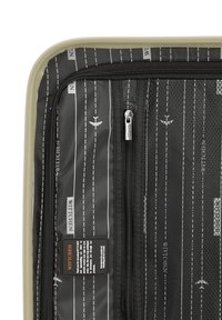 Interior de la maleta con un forro negro que presenta líneas blancas y diseños de aeronaves. Incluye un bolsillo de malla y una etiqueta de marca. Compartimentos con cremallera.