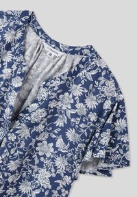 Abito floreale con sfondo navy, caratterizzato da motivi floreali bianchi. Maniche corte e colletto a V, realizzato in tessuto leggero.