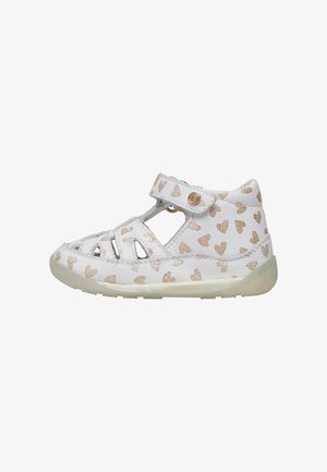 Sandale blanche pour enfants avec découpes et une sangle Velcro. Présente un motif en forme de cœur doré et une semelle texturée pour une meilleure adhérence.
