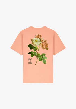 T-shirt in cotone pesco con un motivo floreale che presenta rose rosa e crema, foglie verdi e la scritta "LOVE & ROSES" in nero.