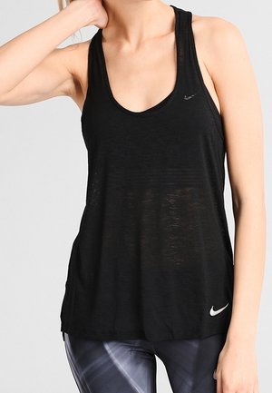 Žena v černém tílku Nike bez rukávů a vzorovaných sportovních legínách s jednou rukou opřenou o krk.