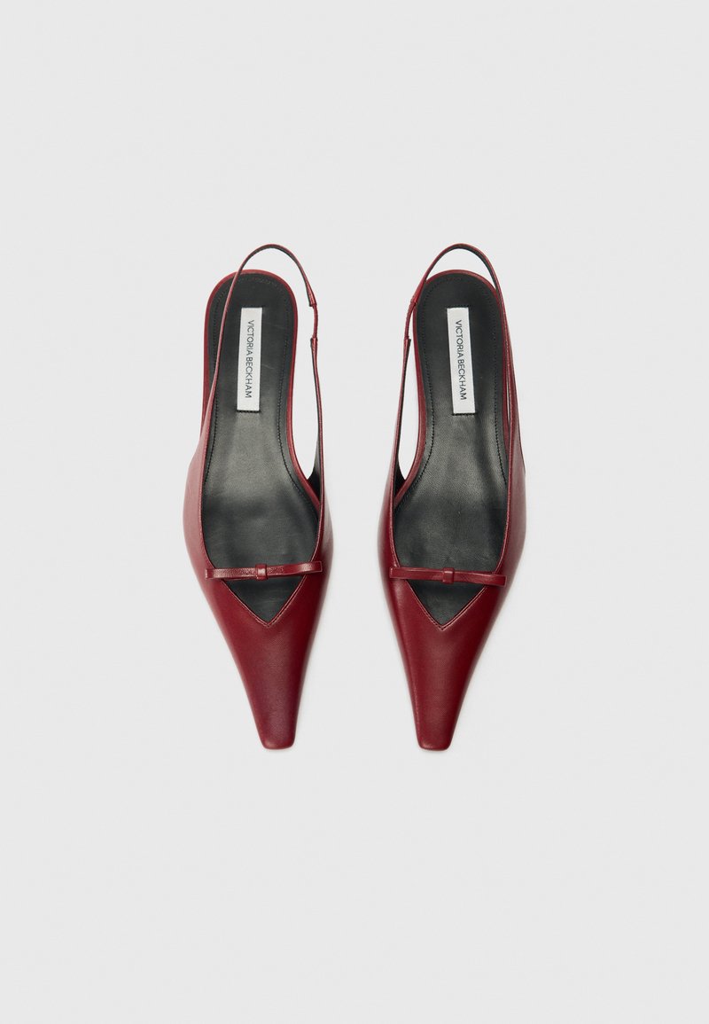 Røde læder slingback sko med spidse tæer, der har et udskåret design. Sort foring og en lille detalje med en accent-rem ved vristen.