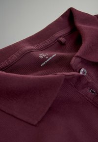 Maroon polo shirt med krave og knapper, størrelse medium, lavet i Bangladesh, vist i nærbillede.