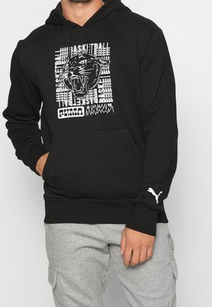 Zwarte hoodie met een witte afbeelding van een brullende panter, de tekst "basketball" en het Puma-logo op de borst en mouw, gecombineerd met een grijze broek.