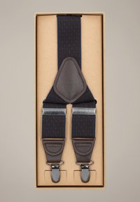 Granatowe szelki w wzory z brązowymi skórzanymi akcentami i srebrnymi metalowymi klipsami, zapakowane w beżowe pudełko do przechowywania lub wręczenia jako prezent.