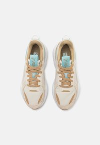 Baskets beiges en mesh et daim, avec des accents bleu clair et une semelle blanche texturée. Dotées de lacets et de languettes pour un enfilage facile.