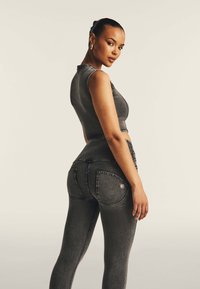 Harmaa farkkukangas crop-top ja korkean vyötärön legginsit, joissa on kaarevat taskut, kontrastivärinen ommel ja sileä pinta.