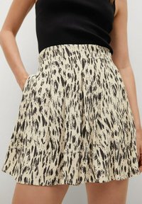 A flared skirt in cream with a black abstract print. Features side pockets and a fitted waistband, made of lightweight fabric.