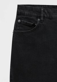 Gros plan sur un jean en denim noir montrant la taille, la passants de ceinture et la poche avant avec des rivets.