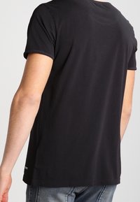 Svart kortärmad T-shirt av mjuk bomull, med rund halsringning och avslappnad passform, med minimal detaljer vid nederkanten.