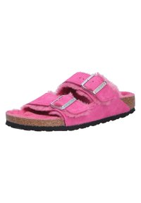 Fuzzy pink sandals with two adjustable straps, cork midsole, and textured black rubber outsole for grip. Feature simple silver buckles.