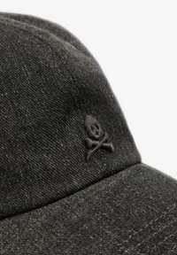 Gorra de mezclilla negra con una superficie texturizada y un logo bordado de calavera y huesos cruzados en la parte frontal. Diseño con visera curva.