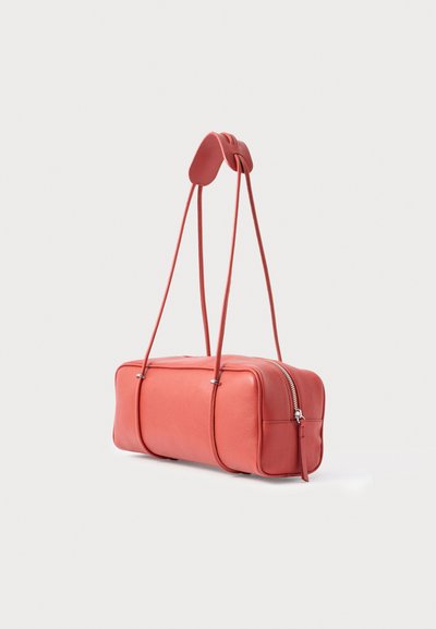 Obdĺžniková koralová kožená kabelka s dlhými tenkými ramennými pásmi a zipsovým zapínaním na jednoduchom bielom pozadí.