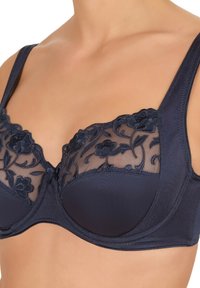 Granatowy stanik z wyszywanym kwiatowym koronką na górze, gładkimi miseczkami na drucie, szerokimi ramiączkami oraz teksturowanym materiałem na korpusie.