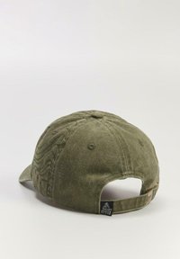 Zielona bawełniana czapka z zakrzywionym daszkiem, teksturowanym materiałem i regulowanym paskiem z tyłu. Posiada przeszywane detale oraz małą metkę z logo.