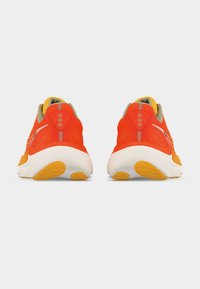 Ζευγάρι από φωτεινά πορτοκαλί αθλητικά παπούτσια με λευκές σόλες, απεικονιζόμενα από πίσω σε απλό λευκό φόντο.