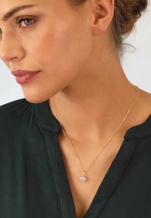 Gold chain necklace featuring a clear, sparkling pendant. The chain has a delicate link design and the pendant is round with multiple facets.