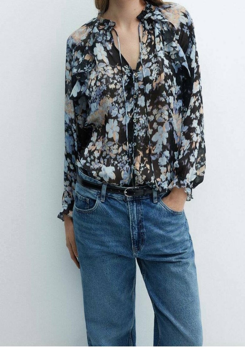 Floral blouse with a black base, featuring blue and peach flowers, button front, puffed sleeves, and a relaxed fit, paired with denim jeans.