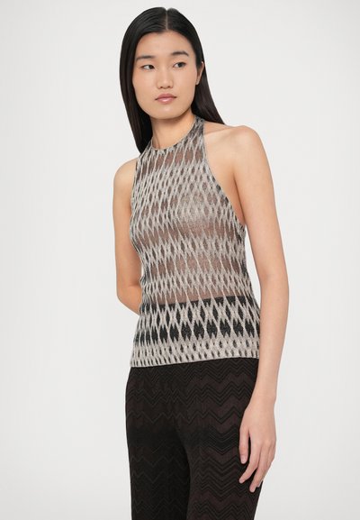 Nyakba akasztható ujjatlan felső áttetsző, gyémántmintás bézs és fekete színekben; texturált, sötét mintás nadrággal párosítva.