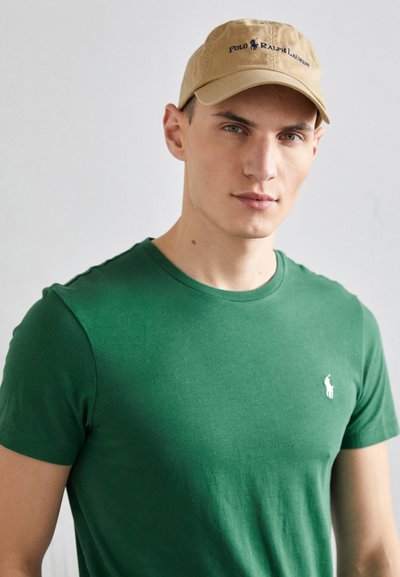 Zaļa īsām piedurknēm t-krekls ar apaļu kaklu un balto polo logo. Beigžē cap ar "POLO RALPH LAUREN" drukāto tumši zilā krāsā.