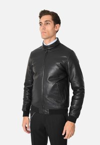 Giacca bomber in pelle nera con colletto alto, zip frontale e due tasche laterali. Presenta polsini a coste e una finitura liscia.