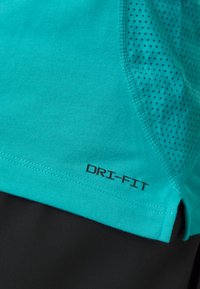 Türkisfarbener DRI-FIT Sportoberteil mit strukturiertem Mesh-Einsatz, kurzen Ärmeln und schwarzem Saum. Flache Nähte und atmungsaktives Material.