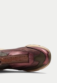 Sneaker in pelle bordeaux e oliva con finitura testurizzata e pannello trasparente, caratterizzata da una forma unica e materiali a contrasto.