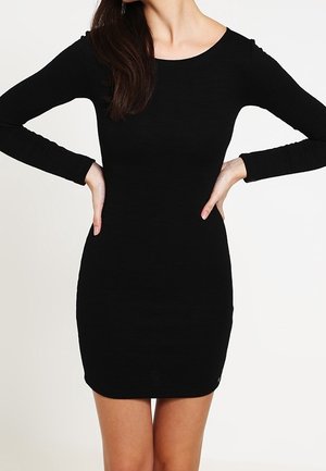 Czarna dopasowana sukienka z długim rękawem, okrągłym dekoltem, prążkowaną fakturą i długością do ponad kolan. Prosty fason bez ozdób.