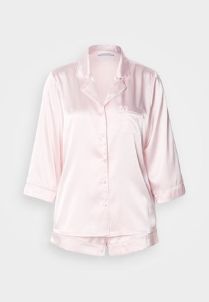 Set ružičastih satenskih pidžama sastavljen od košulje s gumbima, prsima džepom i 3/4 rukavima, u kombinaciji s pripadajućim kratkim hlačama. Glatka tekstura i klasični dizajn.