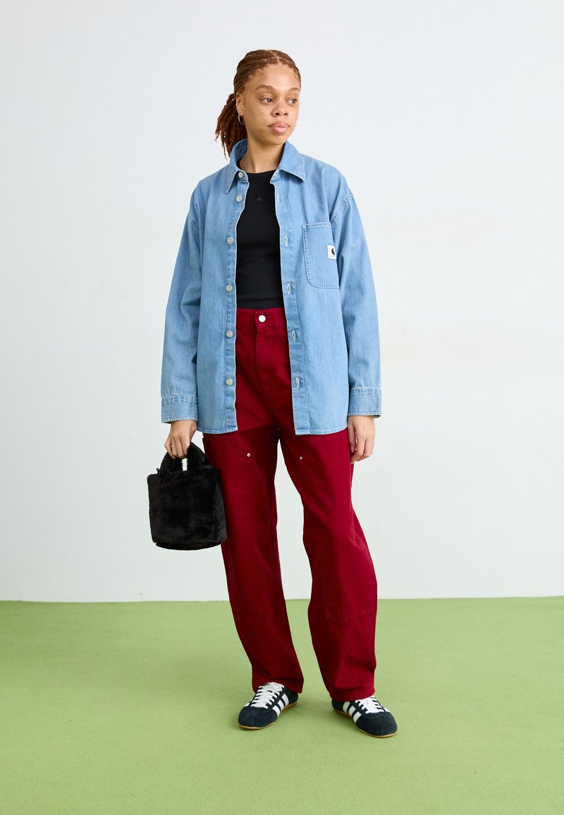 Lichtblauw denim shirt, zwart aansluitend top, bordeaux brede broek, zwart nep-bont handtas, en zwart met witte sneakeraccenten.