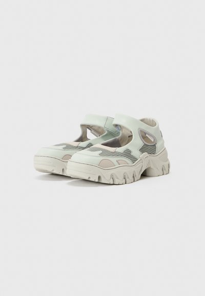 Chaussures en maille et synthétique vert clair avec un design découpé, des accents texturés et des semelles en caoutchouc épaisses présentant des motifs ondulés.