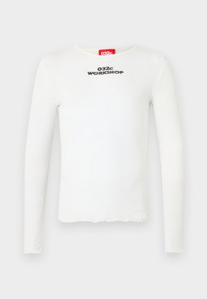 Valge pikkade varrukatega särk pehmest kangast, ümarate kaelaaukudega, musta tikandiga "032c WORKSHOP" tekstiga ja väike logo aktsent ääres.
