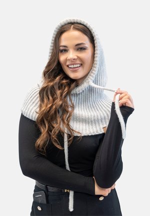 Scaldacollo a cappuccio lavorato a maglia di colore grigio chiaro con una texture a coste e cordini. Indossato sopra una maglietta nera a maniche lunghe.