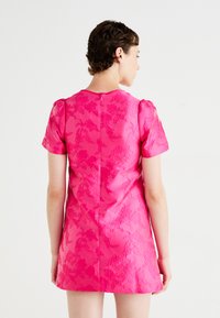 Pink short-sleeve dress with textured floral pattern, fitted design, and back zip closure. Smooth surface and structured silhouette.