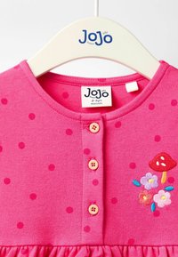 Pinkes Baumwollkleid mit roten Punkten, das über einen runden Ausschnitt, Holzknöpfe und bestickte Blumen sowie ein Pilzdesign verfügt.