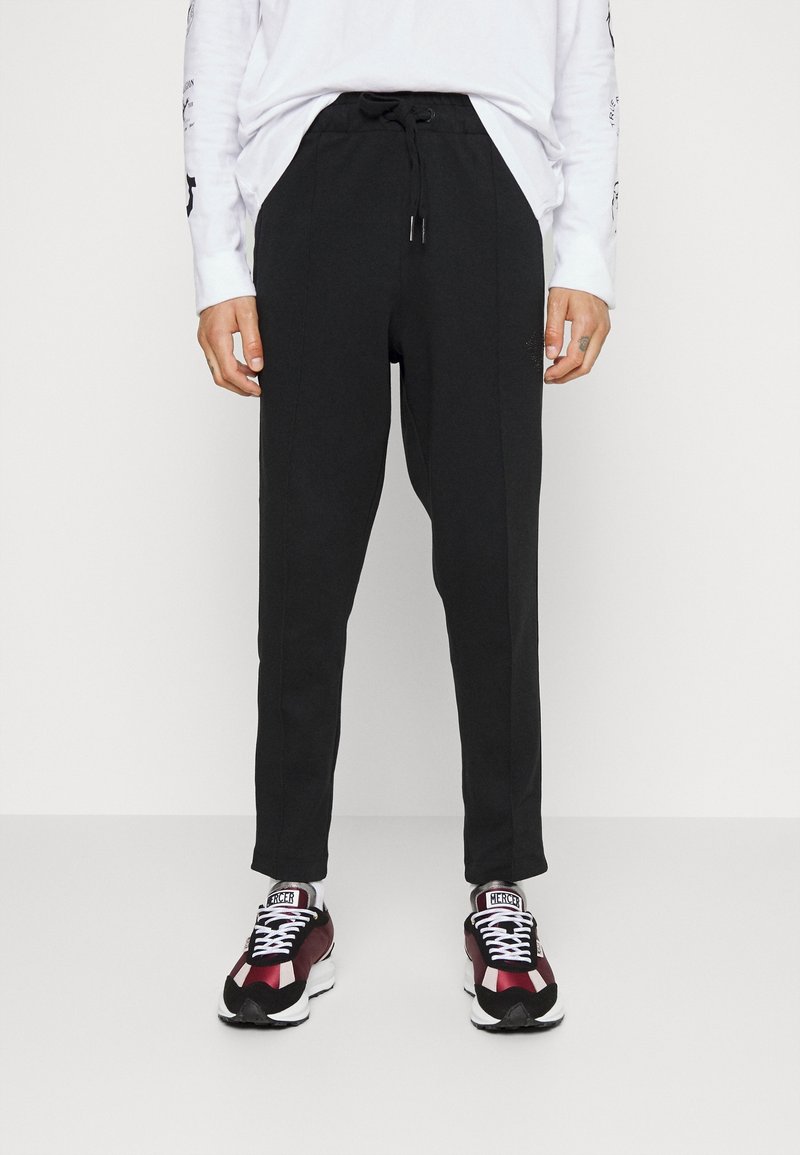 Černé zúžené jogger kalhoty vyrobené z bavlněné směsi s elastickým pasem a šňůrkou. Spárováno s bordó a černými sportovními botami.