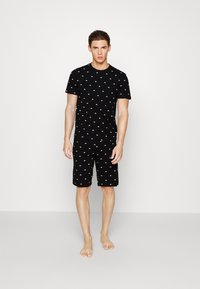 Sort kortærmet T-shirt og shorts sæt, med små hvide tryk overalt. Blødt stof, afslappet pasform og behageligt design.