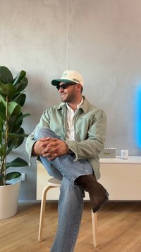 Vaaleanvihreä takki valkoisen paidan päällä, siniset farkut ja ruskeat saappaat. Asusteina valkoinen lippalakki vihreillä yksityiskohdilla ja aurinkolasit.