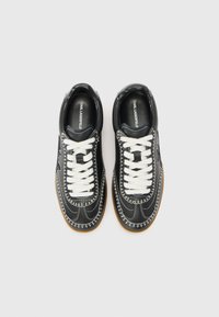 Black leather sneakers with white laces, featuring contrasting stitching, a rounded toe, and a gum sole. Inner lining displays brand logo.