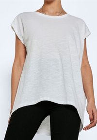 Top bianco a maniche corte con vestibilità rilassata, scollatura rotonda e orlo posteriore leggermente allungato; realizzato in un tessuto leggero e testurizzato.