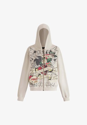 Sudadera con cremallera de color beige claro con un gran estampado gráfico que presenta rosas, corazones y texto en negrita. Textura suave y puños ajustados.