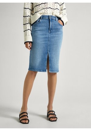 Spijkerbroek potloodrok in lichtblauw met een split aan de voorkant, een hoge taille en een ontwerp met vijf zakken. Gecombineerd met een grofgebreide trui en zwarte sandalen.