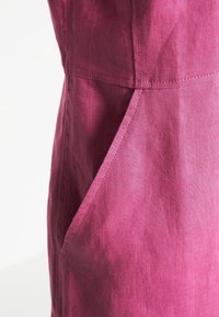 Robe en lin fuchsia à la texture lisse, avec une poche diagonale et des coutures nettes le long des coutures.