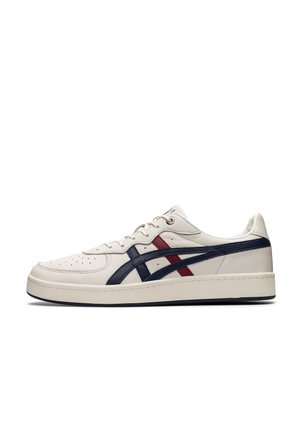 Sneakers with a cream leather upper, navy and red accents, perforated toe, and a thick white sole; features a low-profile design.