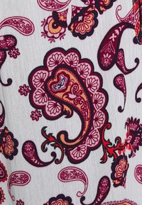 Tecido branco com padrões paisley vibrantes em tons de vermelho, roxo e laranja, com detalhes florais intrincados e contornos pretos contrastantes.