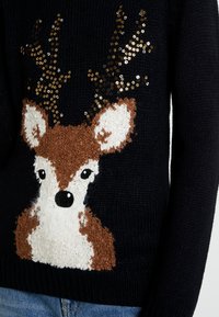 Schwarzer Strickpullover mit einem strukturierten Hirschdesign, verziert mit Pailletten-Geweih, braunen und weißen Akzenten sowie einem runden Gesicht mit schwarzen Augen.