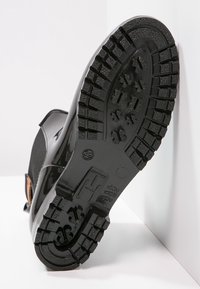 Semelle d'une botte en caoutchouc noire avec de profondes rainures pour l'adhérence et taille 39 marquée près du talon.