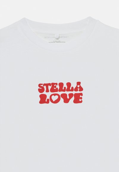 Camiseta branca com o texto vermelho "STELLA LOVE" em letras maiúsculas, arredondadas e em negrito, com um coração dentro do "O" no peito.