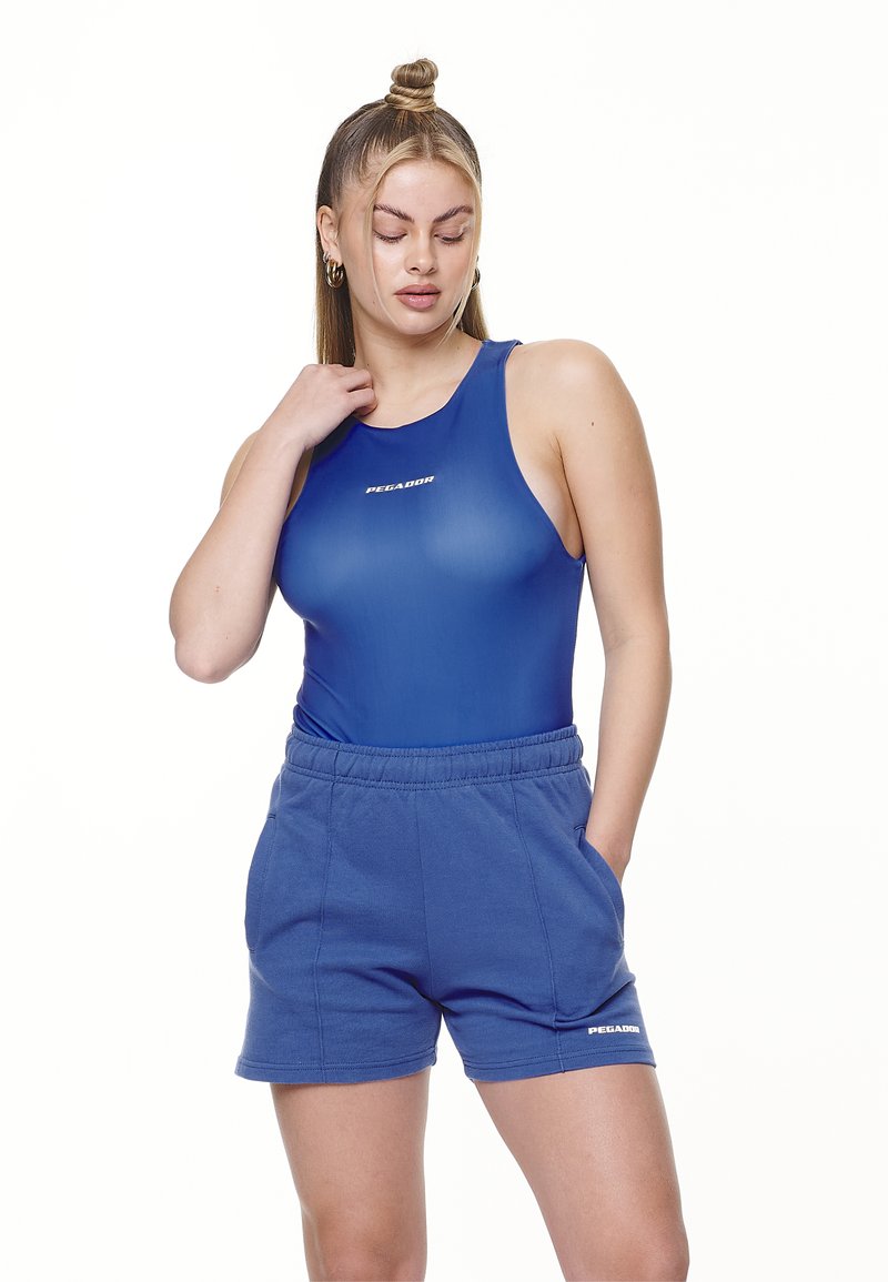 Blå atletisk kroppdrakt med scoop-hals, parret med høytlivede blå shorts med en hvit logo. Materialet ser glatt ut med en tettsittende design.